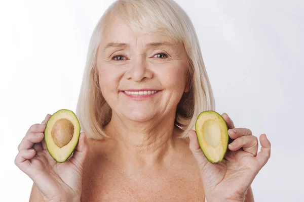 Mujer que tiene dos mitades de aguacate — Foto de Stock