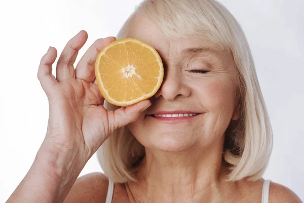 Mujer poniendo una mitad naranja en su ojo — Foto de Stock