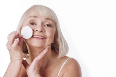 Mutlu yaşlı kadın makyajını çıkarıyor.