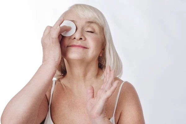 Mulher idosa agradável limpando seu rosto — Fotografia de Stock