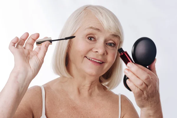 Mujer anciana positiva usando rímel — Foto de Stock