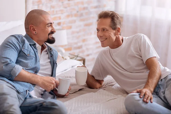 Blij homo paar liggen op het bed en het drinken van thee — Stockfoto