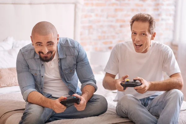 Amigos divertidos jugando con la consola de juegos en la cama — Foto de Stock