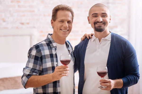 Smiling non-traditional couple drinking wine at home
