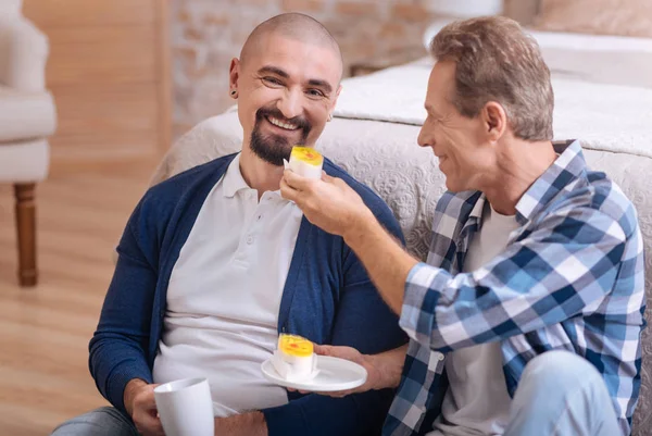 Pareja homosexual comiendo cupcakes en casa — Foto de Stock