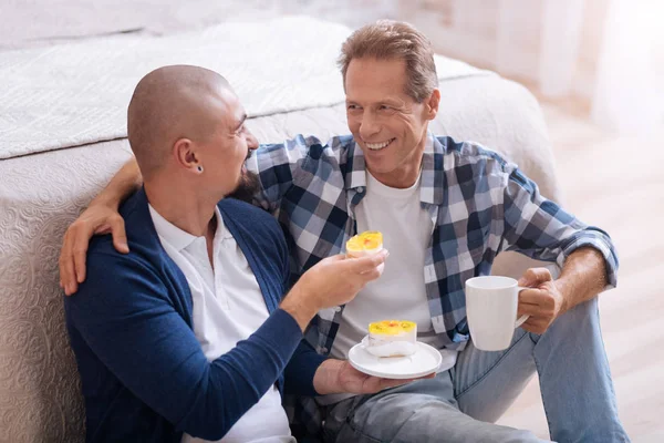 Cheerful non-traditional couple eating bakery together