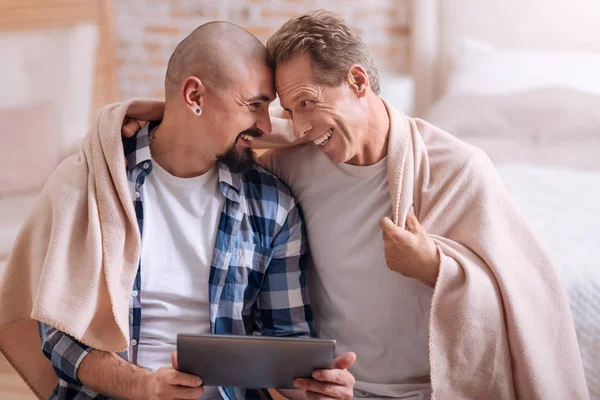 Приятная гей-пара, сидящая и покрытая одеялом — стоковое фото