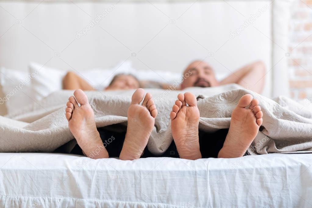 Pleasant non-traditional couple showing their feet