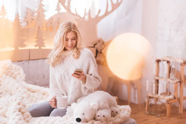 Vrouw met een teawhile met behulp van de telefoon — Stockfoto