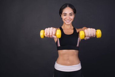 Genç kadın dumbbells her iki elinde tutan güzel