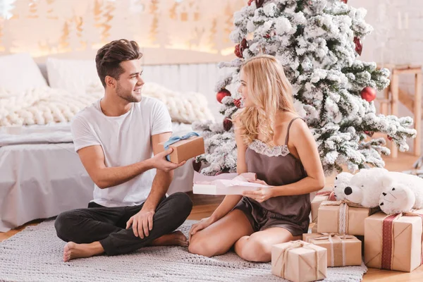 Bonito homem agradável dando um presente de Natal para sua namorada — Fotografia de Stock