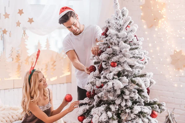 Bom casal positivo decorar a árvore de Natal — Fotografia de Stock