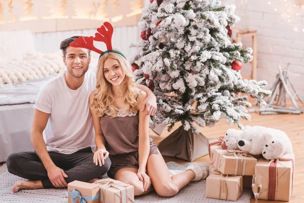 Bonito casal positivo sentado entre presentes de Natal — Fotografia de Stock