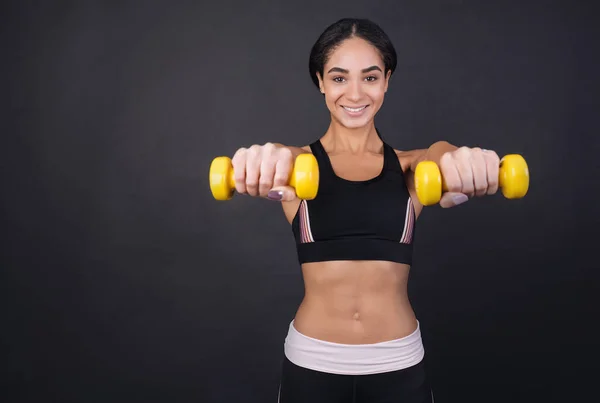 Young pretty woman holding dumbbells in both hands — Stock Photo, Image