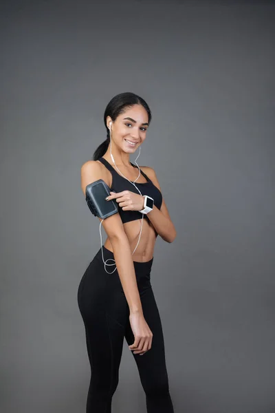 Muskulöse junge Frau mit Gadgets während des Trainings — Stockfoto