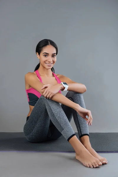 Mooie jonge vrouw zit op de mat — Stockfoto