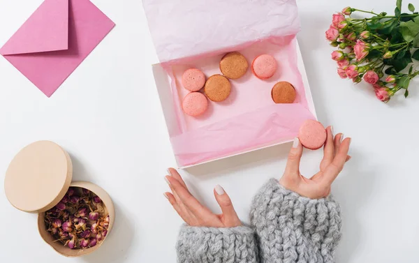 Kleine roze macaroon in handen van een vrouw — Stockfoto