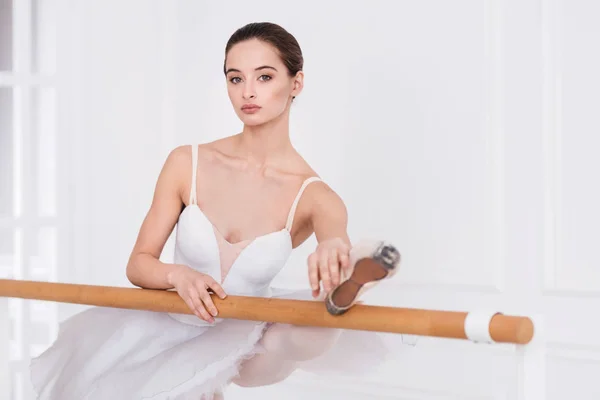 Pretty girl holding her leg on the ballet bar — Stock Photo, Image