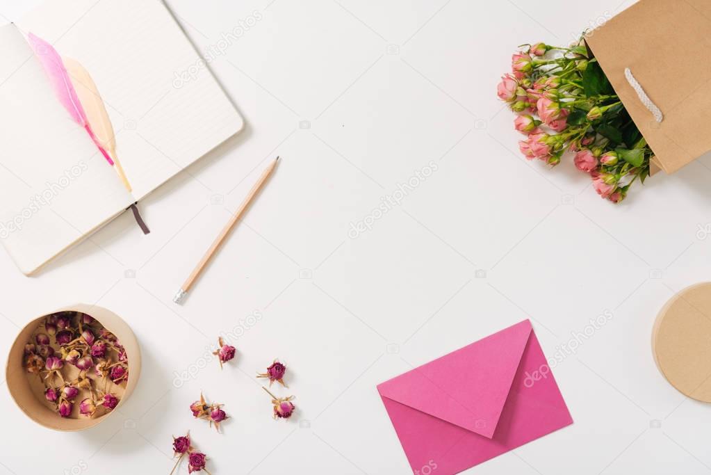 Pink envelope lying near scattered rose buds