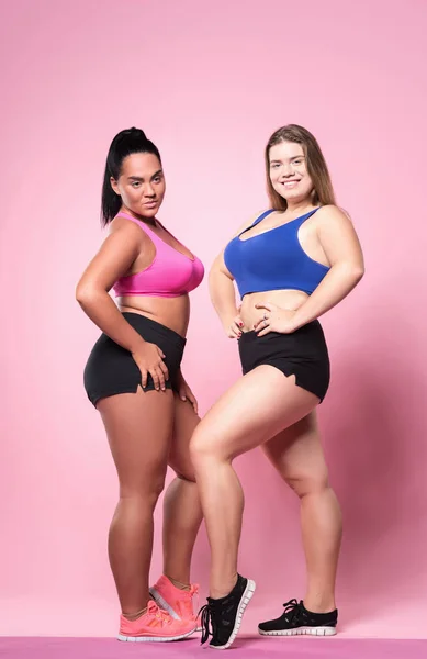 Pareja de mujeres con sobrepeso posando sobre fondo rosa — Foto de Stock