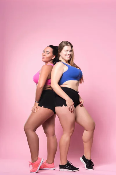 Par de mulheres com sobrepeso posando contra fundo rosa — Fotografia de Stock