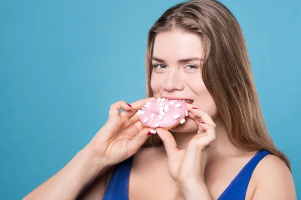 Довольно пухлая женщина ест сладкий пончик — стоковое фото