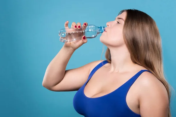 Zijaanzicht van mollige dame drinkwater — Stockfoto