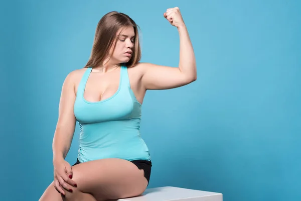 Mulher gordinha olhando para o bíceps — Fotografia de Stock