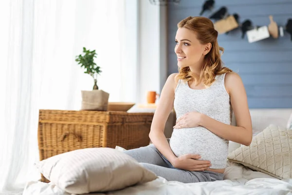 Gravid kvinna som sitter i ett sovrum — Stockfoto
