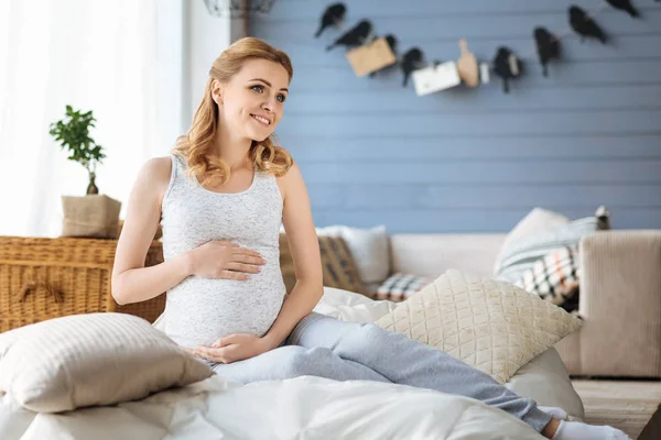 Беременная женщина сидит в своей постели — стоковое фото