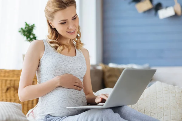 Έγκυος γυναίκα που χρησιμοποιούν φορητό υπολογιστή στο δωμάτιό της — Φωτογραφία Αρχείου