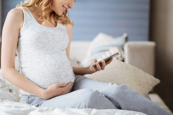 Nahaufnahme einer Schwangeren mit Smartphone im Bett — Stockfoto