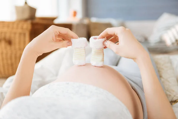 Close up of a pregnant woman demonstrating baby socks — Stock Photo, Image