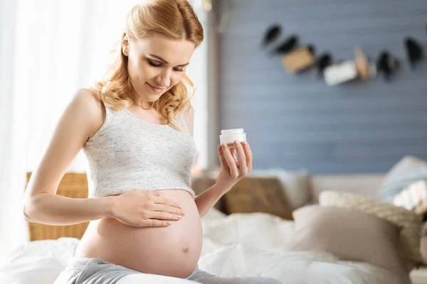 Mulher grávida esfregando suavemente o creme em sua barriga — Fotografia de Stock