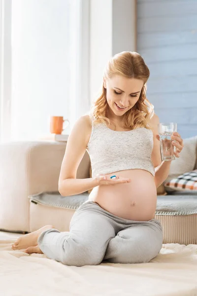 Mulher grávida tomando vitaminas em seu quarto — Fotografia de Stock