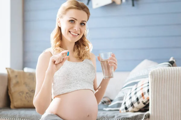 Femme enceinte démontrant une pilule et un verre d'eau — Photo