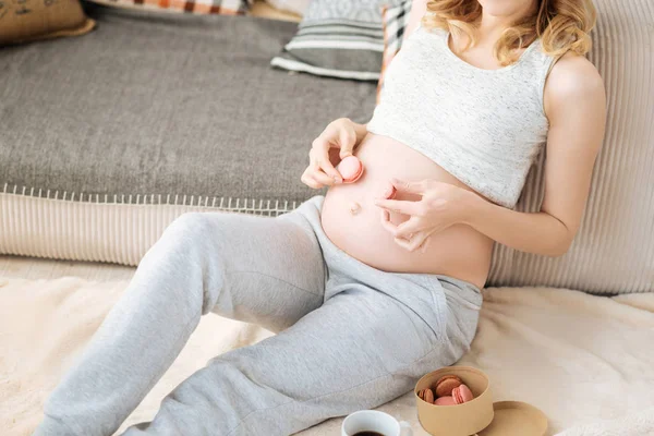 Hamile kadının göbek ve macaroons kapat — Stok fotoğraf