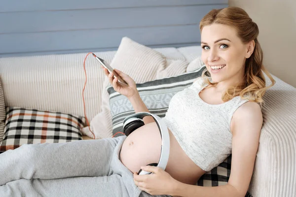 Donna incinta che usa le cuffie sulla pancia — Foto Stock