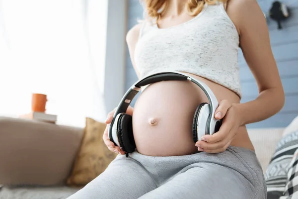 Close up of pregnant woman listening to music on headphones — Stock Photo, Image