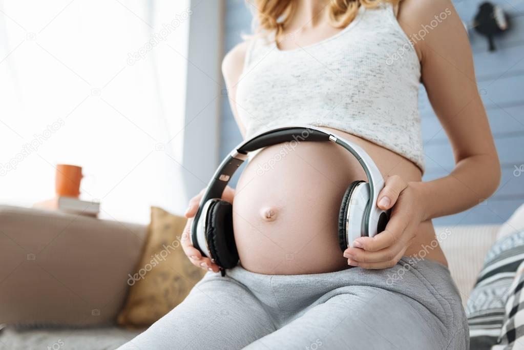 Close up of pregnant woman listening to music on headphones