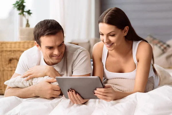 Приємна позитивна пара дивиться на екран планшета — стокове фото