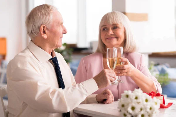 Two lovely elderly people holding up glasses of champagne — Stock Photo, Image