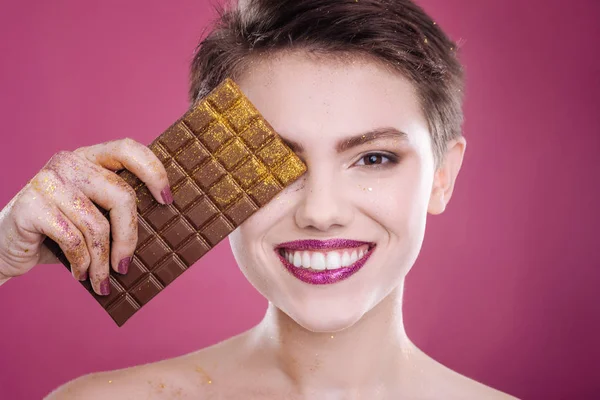 Mujer sonriente alegre sosteniendo chocolate — Foto de Stock