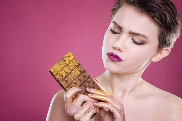 Pleasant young woman holding chocolate bar — Stock Photo, Image