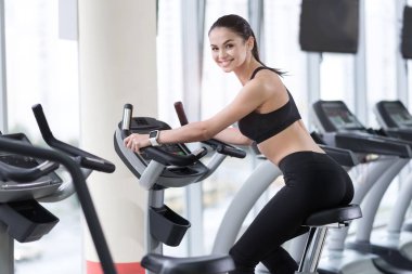 Gülümseyen kadın egzersiz bisikleti üzerinde eğitim