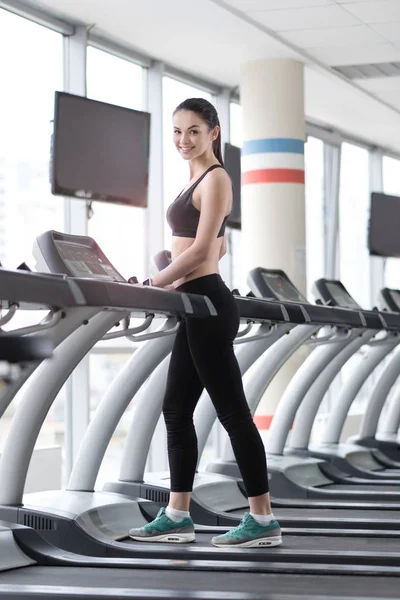 Souriante fille utilisant tapis roulant dans une salle de gym — Photo