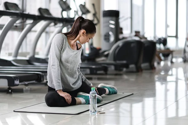 Mujer haciendo estiramiento después del entrenamiento en un gimnasio — Foto de Stock