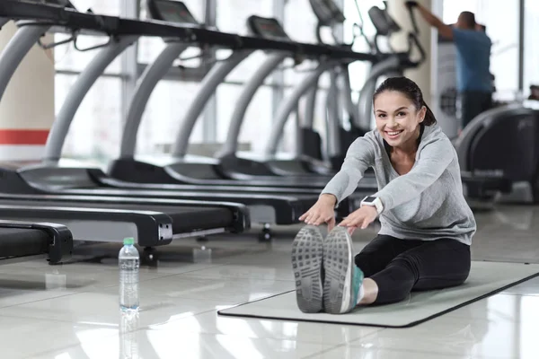 Mujer sonriente haciendo ejercicios de estiramiento — Foto de Stock