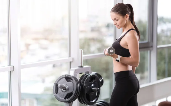 Chica fuerte usando mancuernas en un gimnasio — Foto de Stock