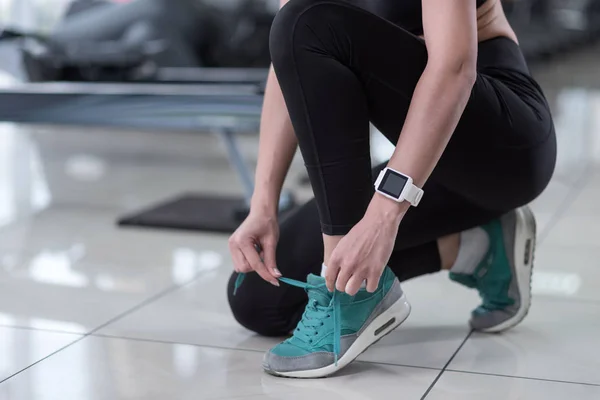 Chica activa atándose los cordones en un gimnasio —  Fotos de Stock